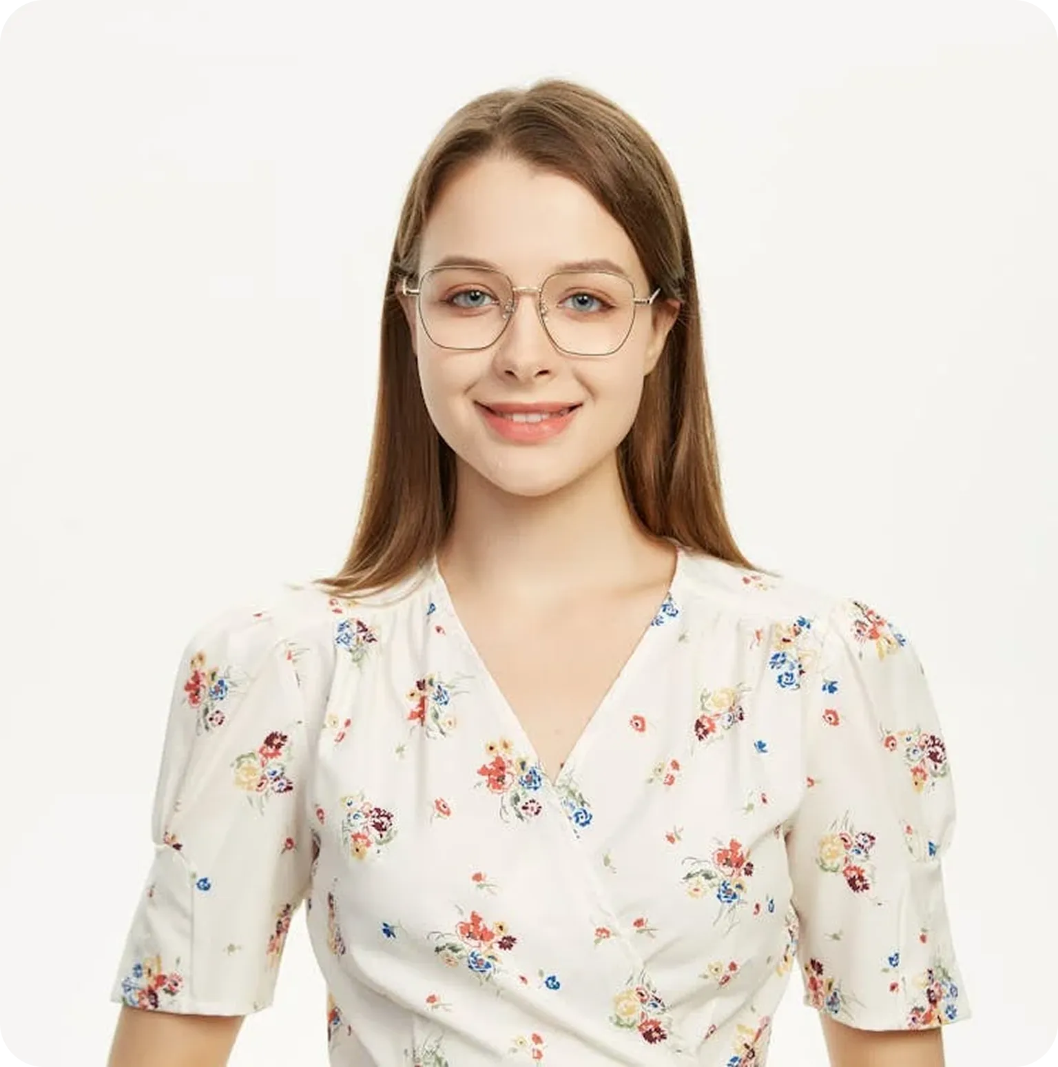 Young woman with long brown hair wearing round glasses and a white floral dress smiling against a plain background.